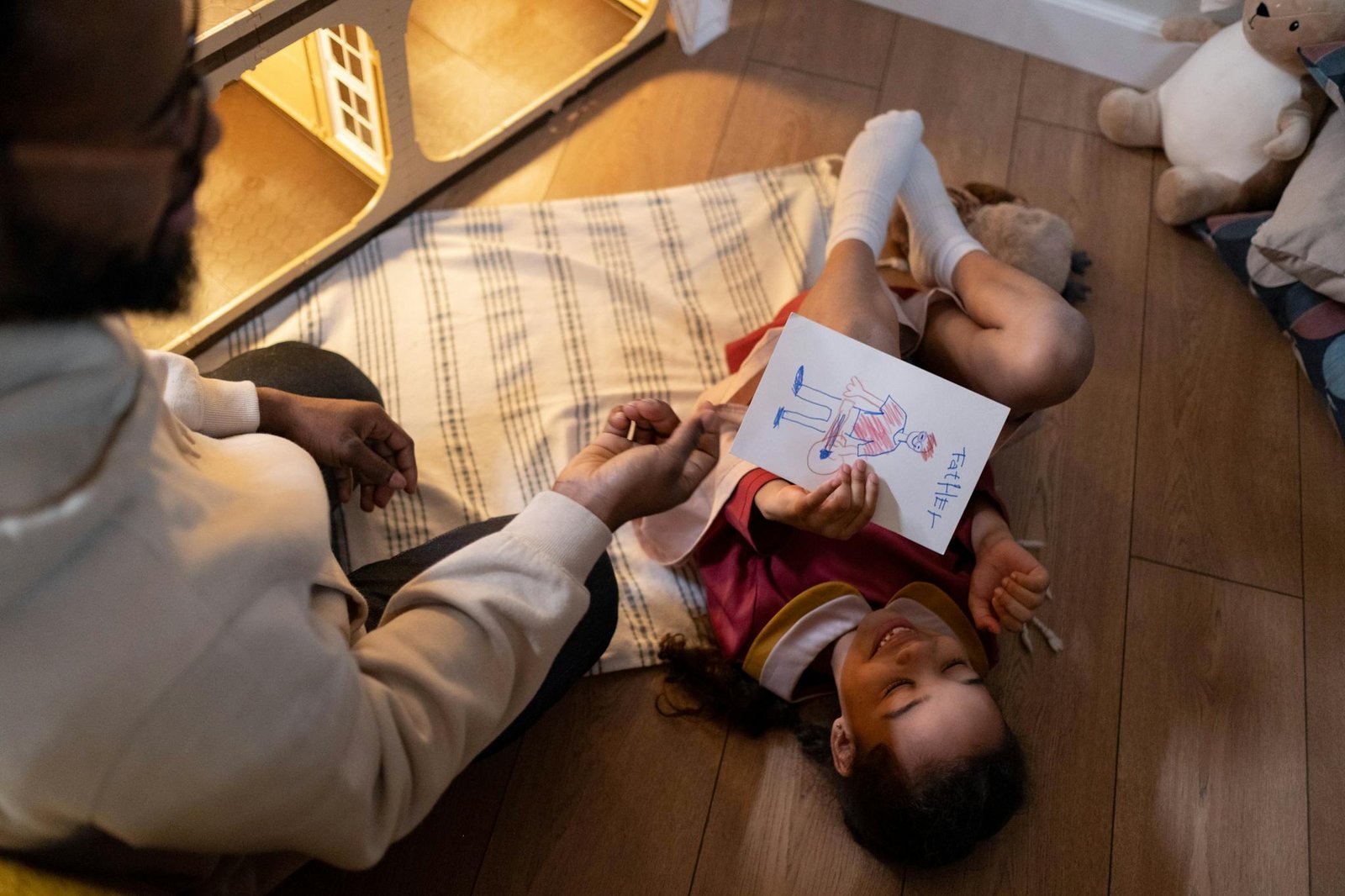 A joyful moment of a father and daughter drawing together, capturing their happiness indoors.
