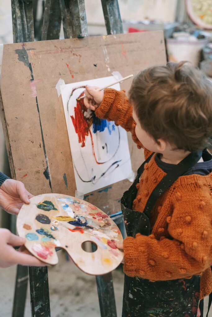 Child painting on an easel with colorful paints, capturing youthful creativity.